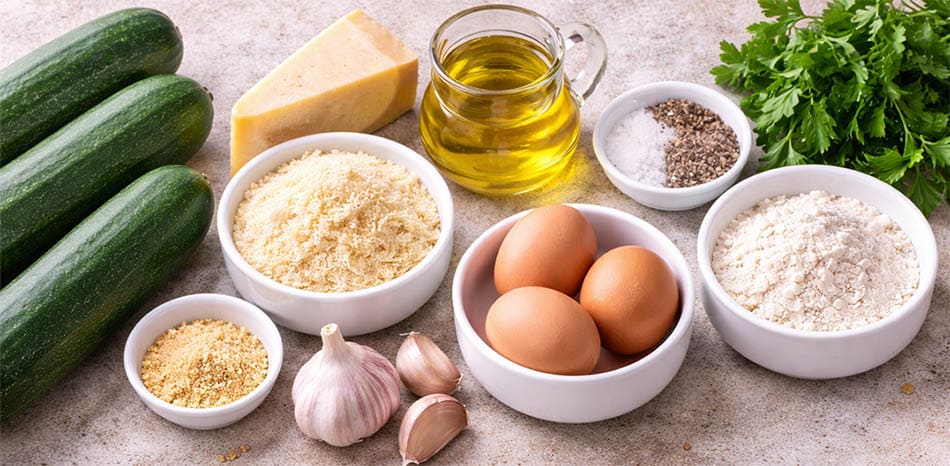 Ingredients for crispy parmesan garlic courgette zucchini sticks including courgettes eggs flour breadcrumbs garlic and parmesan